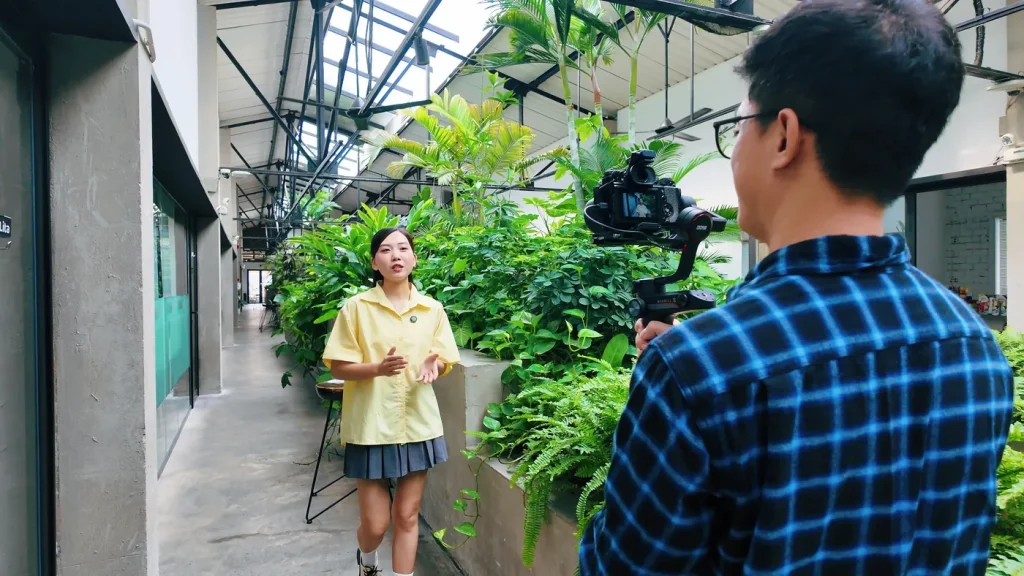 Kha filming an interview with a gimbal in a garden office